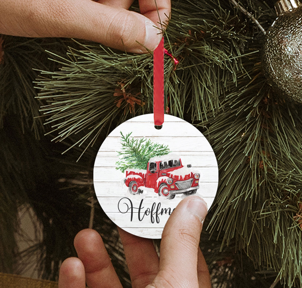 personalized round christmas tree ornament with name under a pickup hauling a tree